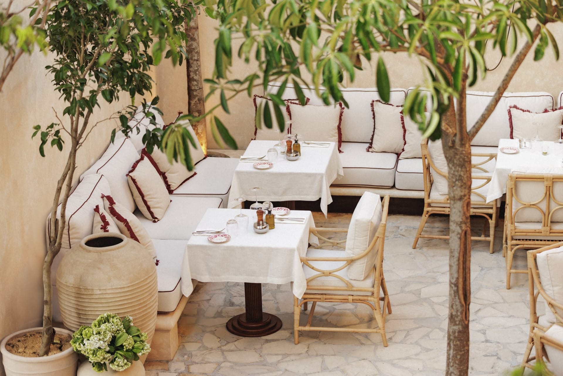 The courtyard, tables laid with white linen and rattan chairs under the trees