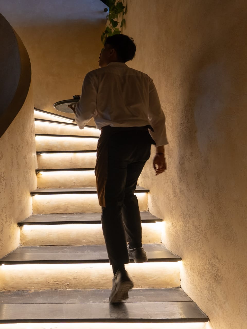 A member of the team carrying a tray up the lit stairs