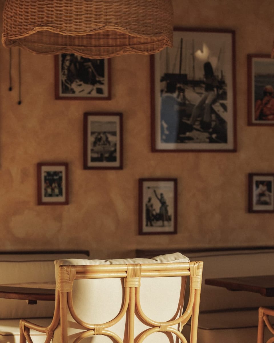 A wall of framed photographs above a rattan chair